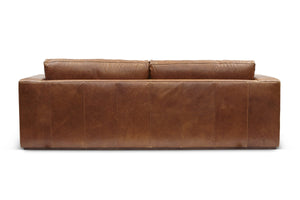 The Bolo Leather Sleeper in Carriage is a brown sofa viewed from the back, showcasing a minimalist design with two large cushions and a smooth texture. Its rectangular shape and muted color make it ideal for both modern and classic interior decor.