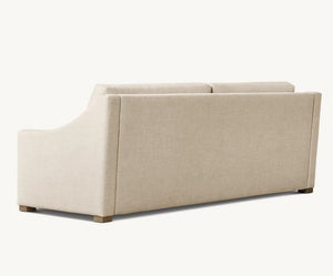 The Belgian Classic Slope Arm Premium Sleeper Sofa, featuring a minimalist design in beige, is shown from the back, highlighting its smooth upholstery and clean lines. The sofa has wooden legs and is set against a plain, light-colored background.