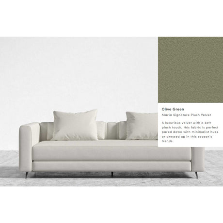 A modern Berlin Sleeper Sofa, featuring a white design with cushions, is set against a plain background. Nearby is a fabric swatch labeled "Olive Green: Mario Signature Plush Velvet," which is characterized as a luxurious velvet with a soft plush touch that aligns with current trends.