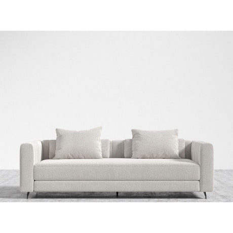A minimalist living room showcases the Berlin Sleeper Sofa in a light gray hue, complete with two matching cushions, set against a plain white wall. The sofa boasts a modern design with straight lines and a luxuriously soft fabric texture. The floor is also light gray, perfectly complementing the sofa's aesthetic.