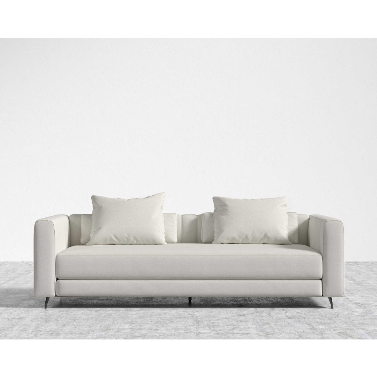 The Berlin Sleeper Sofa, in a sleek light gray, comes with two matching cushions and is positioned on a textured gray area rug against a plain white wall, showcasing its design with clean lines and minimalist aesthetic.
