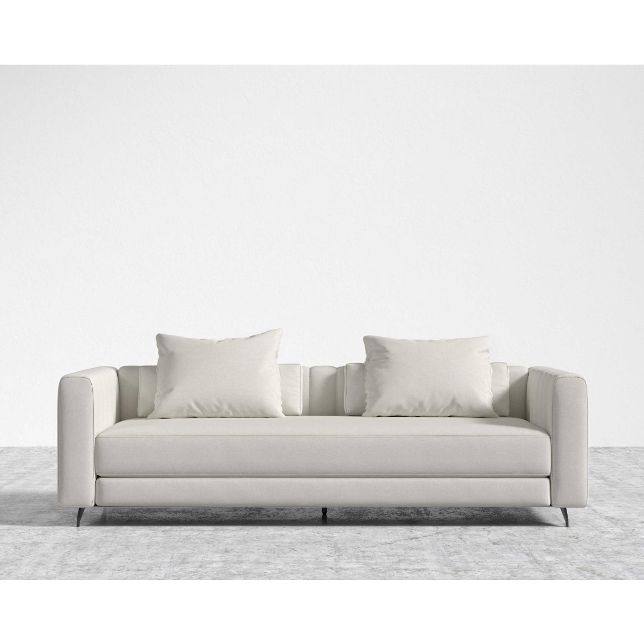 The Berlin Sleeper Sofa, in a sleek light gray, comes with two matching cushions and is positioned on a textured gray area rug against a plain white wall, showcasing its design with clean lines and minimalist aesthetic.