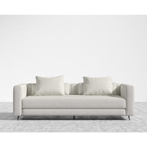 The Berlin Sleeper Sofa, in a sleek light gray, comes with two matching cushions and is positioned on a textured gray area rug against a plain white wall, showcasing its design with clean lines and minimalist aesthetic.