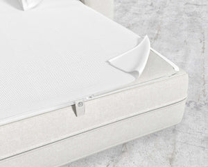 The image features a close-up of a white zippered cover, partially open to reveal the mesh inner layer beneath. This Berlin Sleeper Sofa rests on a light-colored fabric bed base set against a concrete-looking floor.