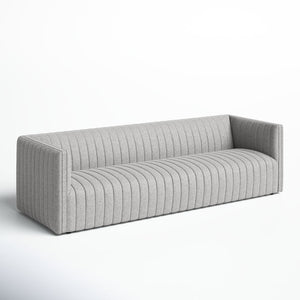 The Brandt 97'' Upholstered Sofa, featuring a modern ribbed design and squared arms in a light gray hue, is displayed against a plain white background. The textured fabric upholstery enhances its appearance, while the sofa’s elongated form sits low to the ground.