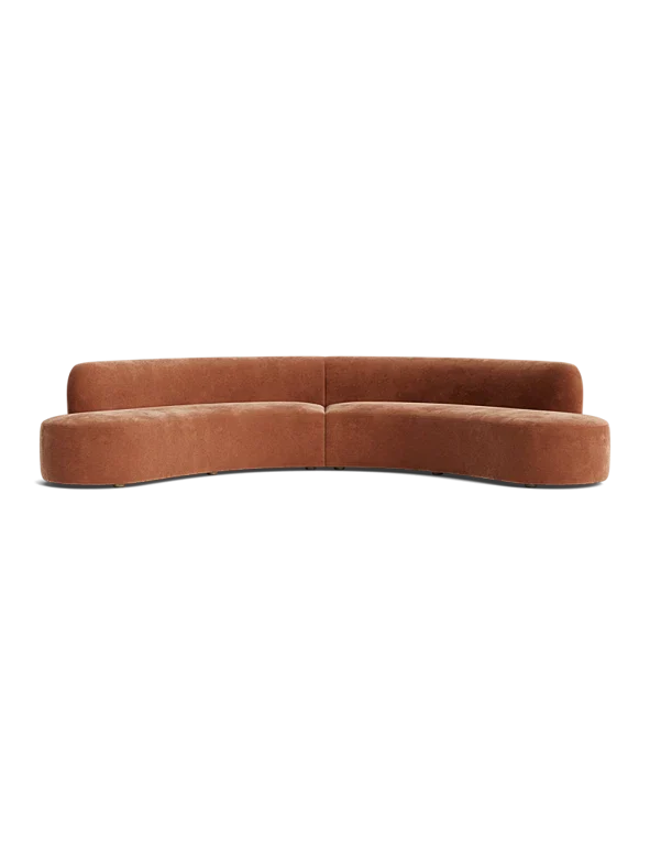 The Cara Sectional Sofa, featuring a brown curved design, sits against a black background with its modern simplicity and hidden legs.