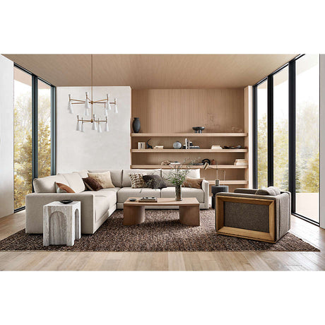 A modern living room with large windows showcases the Gather Sofa 89", a beige sectional complemented by a wooden coffee table and a textured area rug. Decor items are displayed on shelves against the wooden back wall. Pendant lights illuminate the space as natural light pours in through the windows.