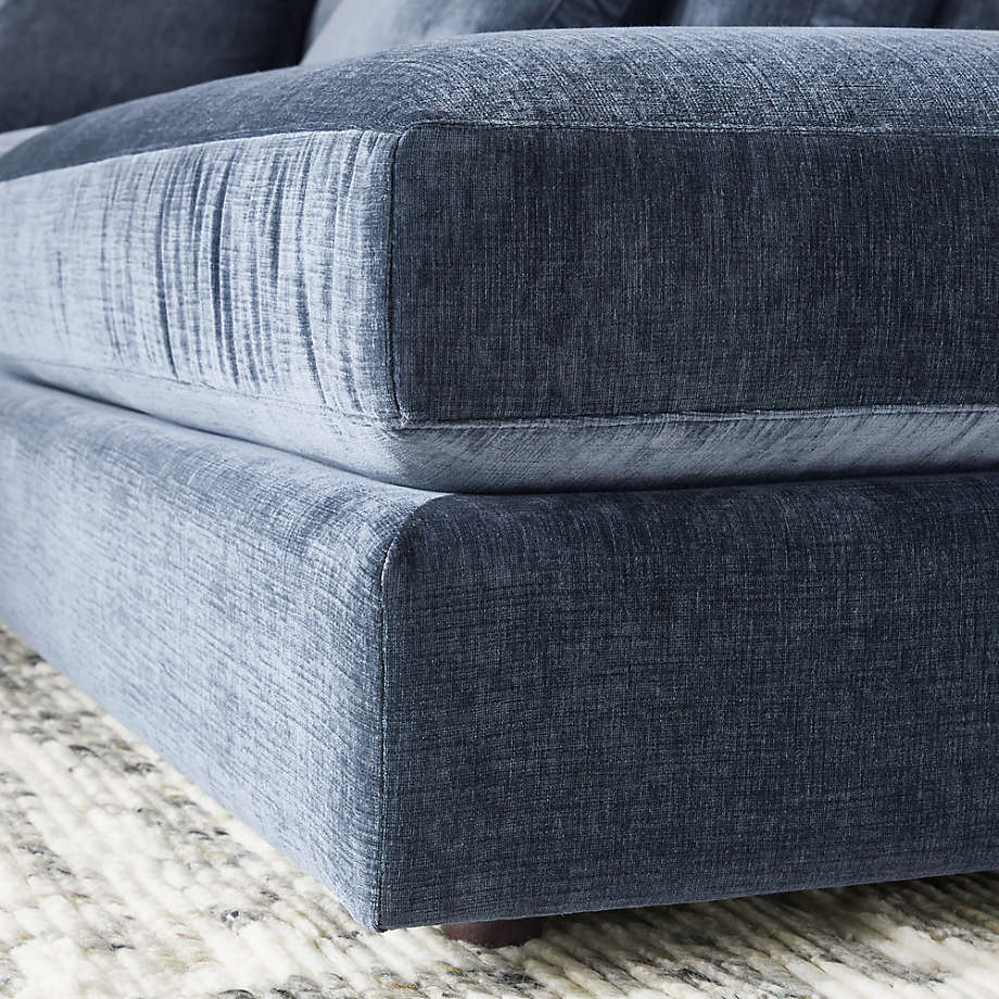Close-up of the Monterey Modular 3 Piece L Shaped Sectional Sofa in a modern blue-gray fabric with a textured finish, resting on a light-colored, patterned rug. The image highlights the sofa cushions and upholstery details.