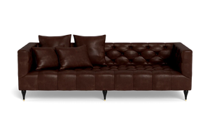 The Ms. Chesterfield Leather Custom Sofa is a dark brown tufted leather piece featuring three seat cushions and four matching throw pillows. It boasts a classic design with black tapered legs and gold tips, set against a black background.