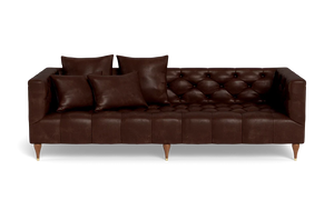 The Ms. Chesterfield Leather Custom Sofa is a dark brown leather piece featuring tufted cushions and paired with four matching pillows. It stands on short wooden legs and is showcased against a plain black background.
