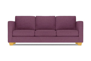 The Catalina Sofa, with its modern design in a purple hue, comes complete with three cushions. It features straight arms and light wooden legs, all showcased against a white background.