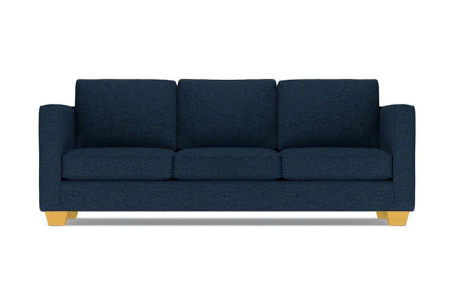 The Catalina Sofa is a dark blue three-seater featuring square cushions and light wooden legs, set against a white background.