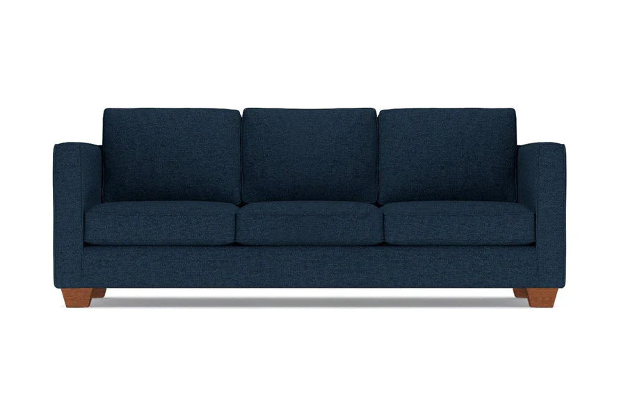 The Catalina Sofa, featuring a dark blue color, is a three-seater with square armrests and wooden legs, shown from the front against a white background.