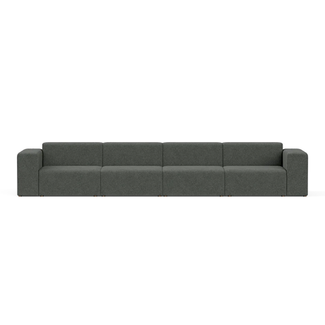 The Four-Seater Form Sectional is a long, modern sofa in dark gray featuring four evenly spaced sections and boxy armrests, set against a plain white background. Its minimalist design provides ample seating space.