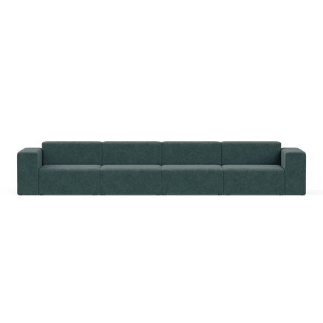 The Four-Seater Form Sectional is a spacious dark green modular sofa with six sections, featuring armrests on both ends, set against a plain white background and boasting a minimalist and contemporary design.