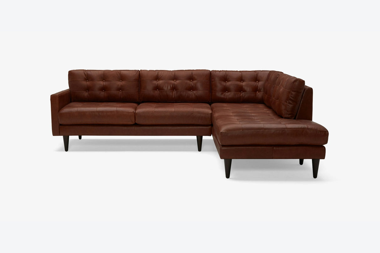 The Eliot Leather Sectional with Bumper, a brown L-shaped sofa featuring tufted backrest and cushions, supported by dark wooden legs, is set against a plain white background.