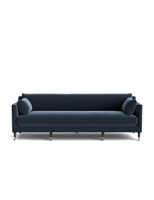 Introducing the Fabienne Sofa: a contemporary piece in dark blue, featuring clean lines and two cylindrical pillows at each end. The sofa is elevated on slender, tapered legs that contrast elegantly with the dark upholstery. Its sleek design is accentuated by a solid black background.