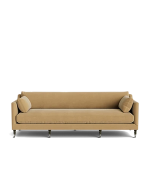 The Fabienne Sofa, in a beige finish, features two matching cushions on each end. It showcases a clean, minimalist design with tapered wooden legs and a low backrest, set against a plain white background.