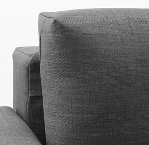 A close-up of the FRIHETEN Sleeper Sofa showcases its modern dark gray fabric, emphasizing the textured upholstery and the clean, angular lines of its armrest and back cushion. The fabric is tightly woven, contributing to its minimalist design.