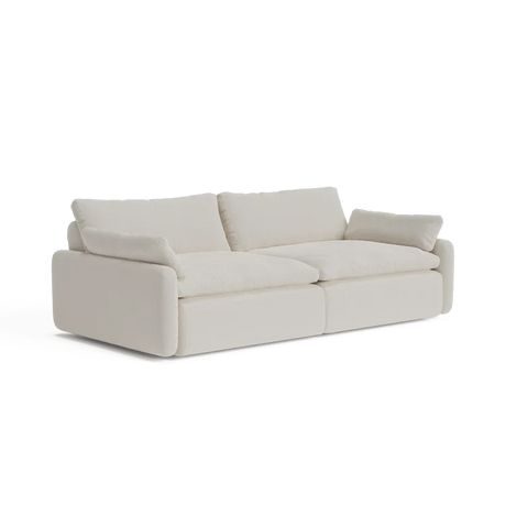 Introducing The Sink Down Sectional, a trendy white sofa with a sleek modern design. It showcases thick cushions and armrests, making it the ideal choice to bring a contemporary feel to any living room.