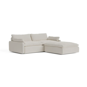 The Sink Down Sectional is a modern, light beige sofa with plush cushions and a left-hand chaise lounge. It boasts a minimalist design and embodies both comfort and elegance.