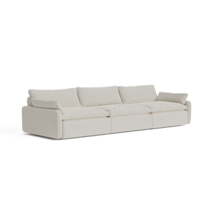 A contemporary, beige three-seater sectional named "The Sink Down Sectional" featuring plush cushions and a minimalist design, set against a white backdrop.