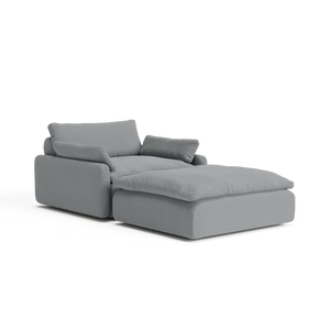 Introducing The Sink Down Sectional, a contemporary gray sectional perfectly paired with an ottoman, showcasing plush cushioning and a sleek, minimalist design against a pristine white backdrop.