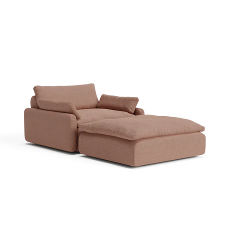 Introducing The Sink Down Sectional, a modern chaise lounge in a stylish brown hue, equipped with plush cushions. Its design includes an extended section for enhanced leg support, providing a contemporary and comfortable seating solution.