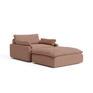 Introducing The Sink Down Sectional, a modern chaise lounge in a stylish brown hue, equipped with plush cushions. Its design includes an extended section for enhanced leg support, providing a contemporary and comfortable seating solution.