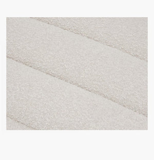 Close-up of the Float Sofa's textured fabric with a soft, off-white color, featuring a subtle pattern of horizontal, puffy stripes.