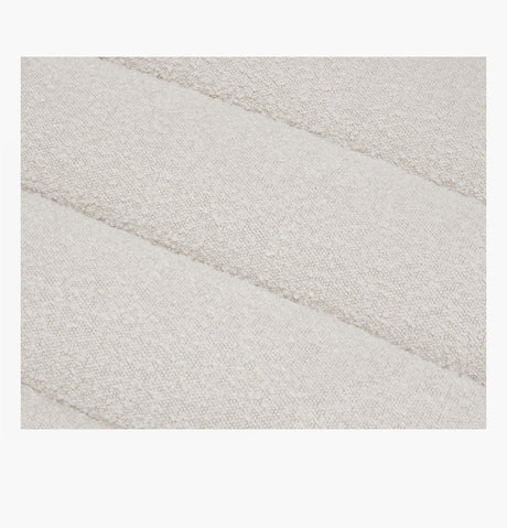 Close-up of the Float Sofa's textured fabric with a soft, off-white color, featuring a subtle pattern of horizontal, puffy stripes.