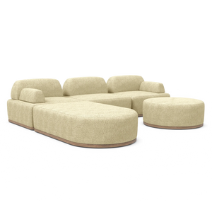 Introducing the Magna Preconfigured Sectional—a contemporary, beige-colored modular sofa with rounded edges, paired with a coordinating round ottoman. This sofa boasts plush cushions and a sleek texture, all displayed against a simple white background.