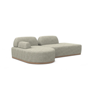 The Magna Preconfigured Sectional is a modern, gray, two-piece modular sofa with textured fabric and a wooden base. It boasts rounded edges and an asymmetrical backrest, making it perfect for a contemporary living room.