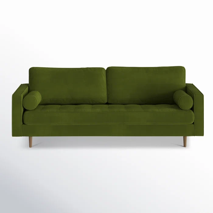 The Geo 84'' Upholstered Sofa, dressed in olive green velvet, features two square back cushions and cylindrical bolster pillows on each end, and is set on mid-century modern wooden legs against a plain white background.