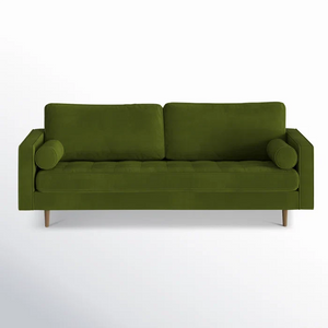 The Geo 84'' Upholstered Sofa, dressed in olive green velvet, features two square back cushions and cylindrical bolster pillows on each end, and is set on mid-century modern wooden legs against a plain white background.