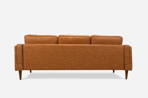 Back view of the Albany Sofa in camel brown vegan leather, featuring three seat cushions and four tapered wooden legs, set against a plain white background.