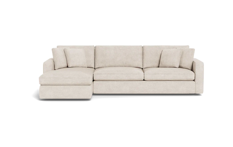The James 3 Seat Left Chaise 92" Sectional is a beige sofa with an extended left-side chaise, three seat cushions, multiple back cushions, and is showcased against a black background. Its modern and minimalist design highlights clean lines.