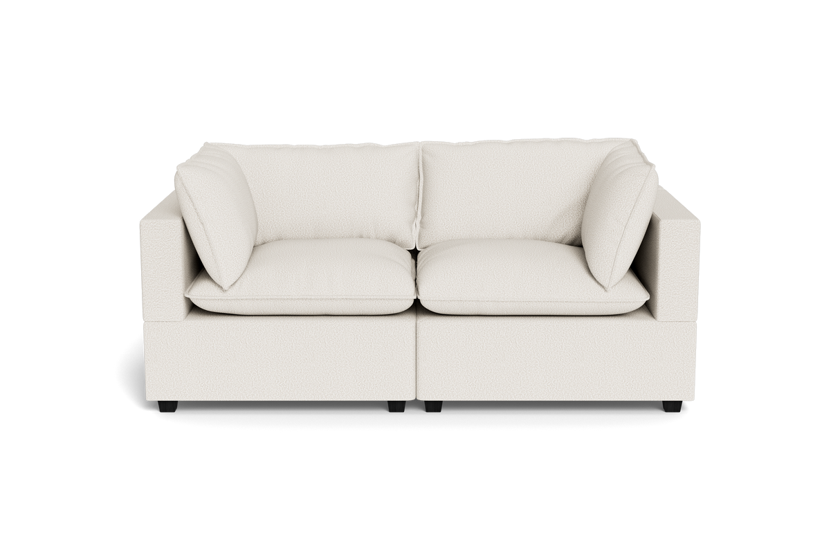The Kova Pillow Cushion Sofa 86" is a modern, light beige two-seater with square armrests and plush cushions, shown from the front against a plain black background.