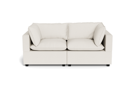 The Kova Pillow Cushion Sofa 86" is a modern, light beige two-seater with square armrests and plush cushions, shown from the front against a plain black background.