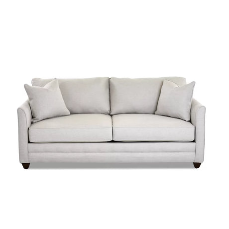 The Kodie 76.5" Upholstered Sleeper Sofa is a light gray piece featuring two seat cushions and matching back cushions, complemented by two square pillows on each side. It boasts a clean, modern design with slightly flared arms and rests on short dark wooden legs.