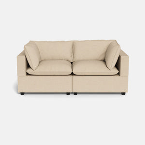 The Kova Pillow Cushion Sofa 86" is a beige two-seater with square arms, two seat cushions, and two back cushions, set against a white background.