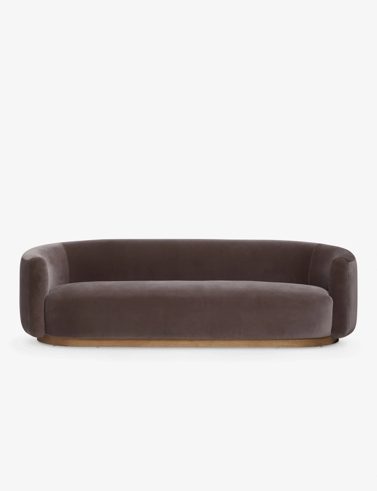 The Lowry Sofa is a stylish piece with its dark gray velvet upholstery, rounded arms, and low backrest. Set against a plain white background, it boasts a sleek, minimalist design with a wooden base that gives it an elegant and contemporary appearance.