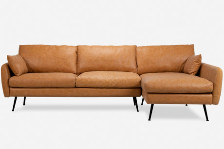 The Park Sectional Sofa is a contemporary light brown leather piece featuring three large cushions and an attached right-side chaise, complemented by sleek black legs. It is displayed against a plain white background.