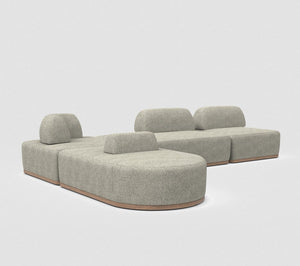 The Magna Preconfigured Sectional is a modular gray fabric sofa with rounded edges and a wooden base, arranged in a U-shape. Its minimalistic design is showcased against a plain, light background.