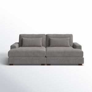 The Etta Avenue Mordecai 90'' Square Arm Sofa is a gray, two-seater with a ribbed texture and comes with matching cushions. It features wide armrests and rests on wooden legs, set against a plain white background.