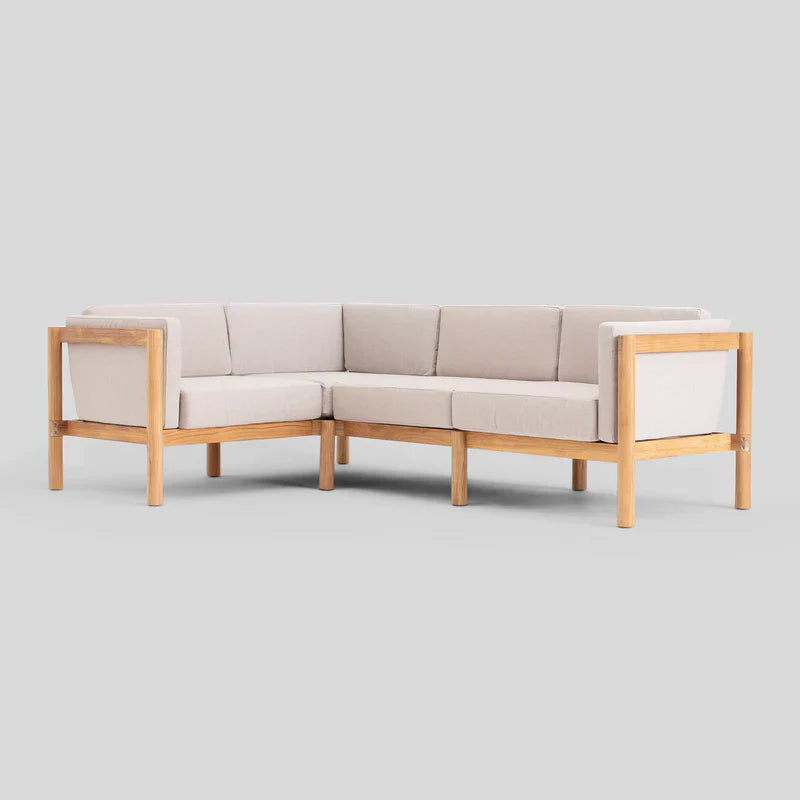 The Haven Sectional is a beige L-shaped sofa featuring a wooden frame and legs, with clean lines and a minimalist design, set against a plain gray background.