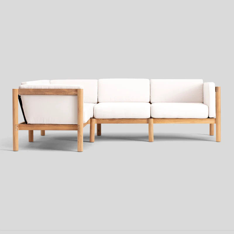 The Haven Sectional, a minimalist wooden-framed sofa with white cushions, is showcased against a plain gray background. It boasts clean lines and soft, comfortable upholstery.