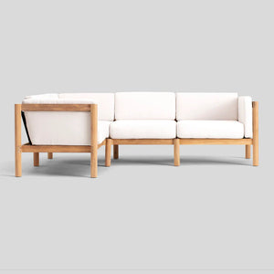 The Haven Sectional, a minimalist wooden-framed sofa with white cushions, is showcased against a plain gray background. It boasts clean lines and soft, comfortable upholstery.