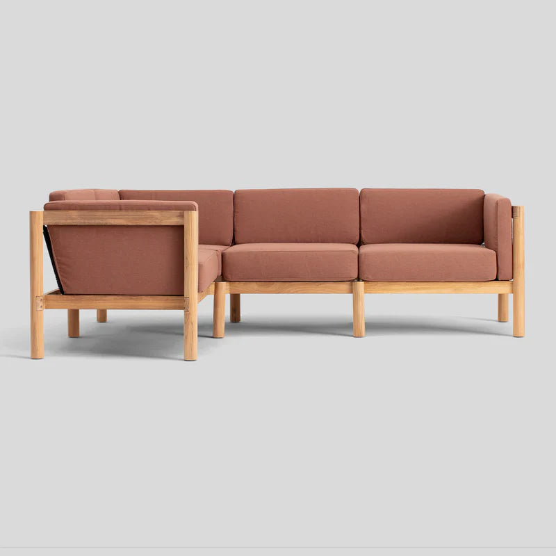 The Haven Sectional features a modular L-shaped design with a light wood frame and muted terracotta cushions, set against a plain gray background.