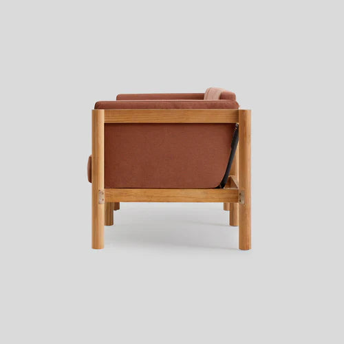 Side view of the Haven Sofa featuring a wooden frame and brown upholstery, set against a plain light gray background. The minimalist design highlights the clean lines and natural wood texture.